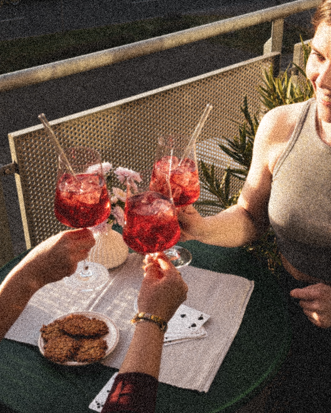 Drei Freunde auf dem Balkon die mit einem GRANADA NIGHTS Spritz anstoßen.