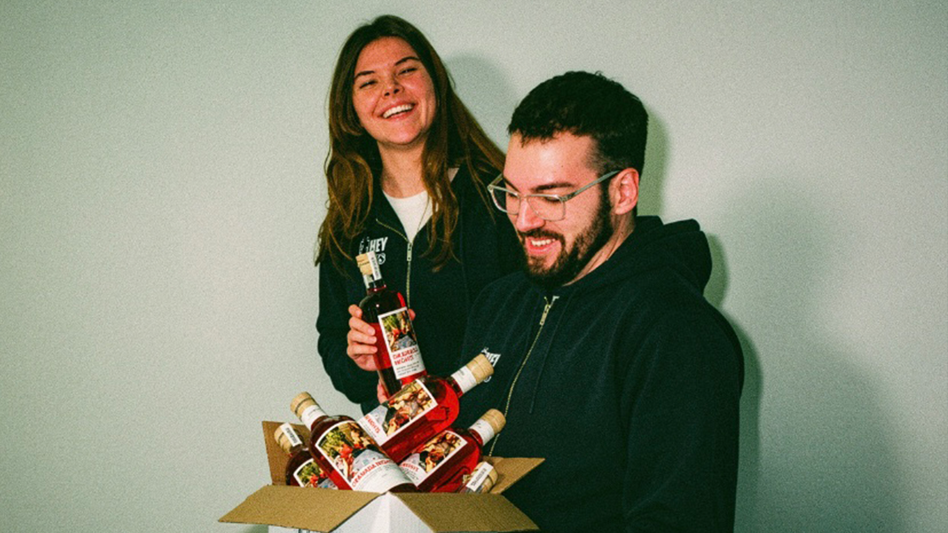 Zwei Personen, Hanna und Tim, die Gründer von HEYBEVS mit einer Kiste GRANADA NIGHTS.